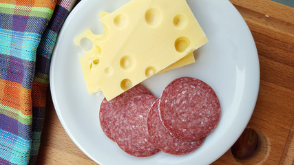 Cheese and salami on white plate