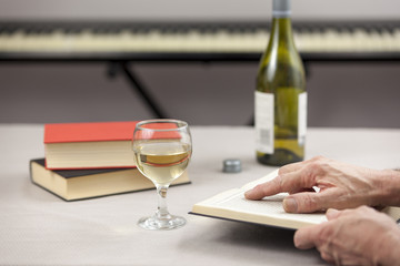 Person reading at table with a glass of wine