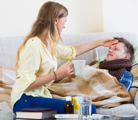 Wife taking care of young husband with flue at home