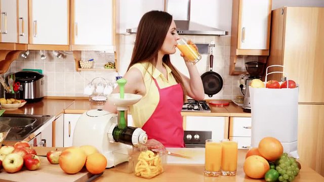 Woman make orange juice in juicer machine drinking 4K