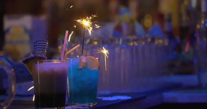 Close-up shot of bartender making presentation of cocktails before the serving, he firing sparkler in one of them