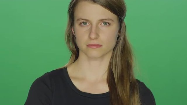 Young women looks sad and cries, on a green screen studio background