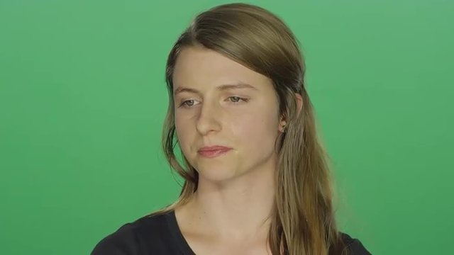 Young women looks sad and cries, on a green screen studio background