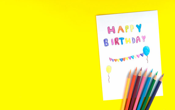 Happy birthday card kid handwriting on yellow background. Children drawn and paint colorful text with colored pencils on paper. For fill text on mock-up or poster. Top view.
