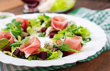 Salad with baked beet, blue cheese, ham and green mix with pesto