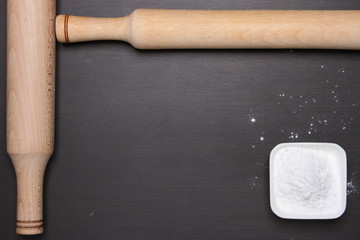 Rolling pin and flour on table. Top view.