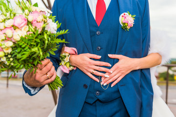 Groom hugs bride with bouquet of flowers.