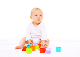 Baby playing with colorful toys on white background