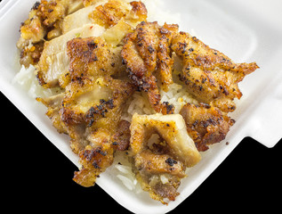 Grilled chicken over rice in foam box isolated on black background with clipping path