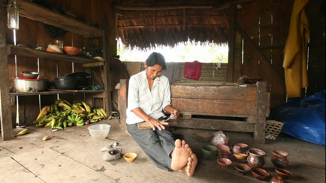 Adult woman creating pottery in a picturesque rural setting amidst the breathtaking landscapes of Ecuadorian Amazonia.