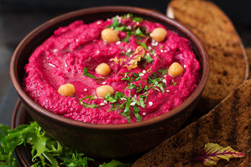 Roasted Beet Hummus with toast in a ceramic bowl on a dark background
