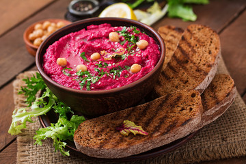 Roasted Beet Hummus with toast in a ceramic bowl on a wooden background