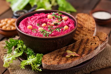  Roasted Beet Hummus with toast in a ceramic bowl on a wooden background © timolina