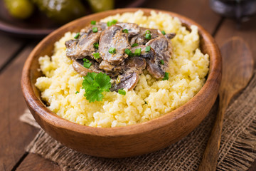 Millet porridge with mushrooms in a wooden bowl