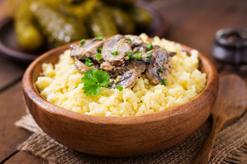 Millet porridge with mushrooms in a wooden bowl