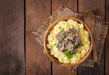 Millet porridge with mushrooms in a wooden bowl. Top view