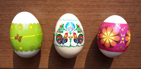 Three colorful Easter eggs on a brown table
