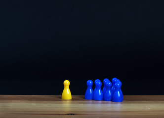 ilsolated yellow pawn and group of blue pawns on