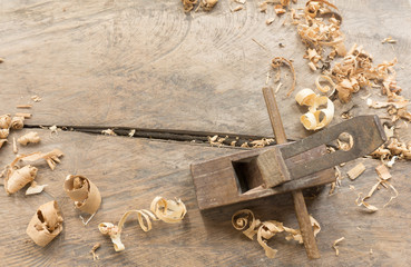 Old plane hand tool upper view. Old rusty and dirty carpenter`s wooden hand tools lying on a wooden table with sawdust background.
