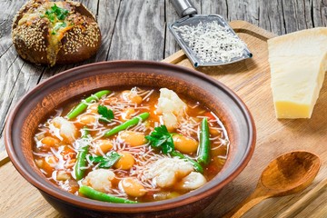 Minestrone vegetable soup with beans, cauliflower, tomatoes, close-up, top view