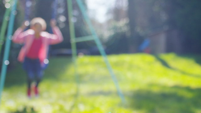 Blurred background of a child on a swing in the garden, in slow motion