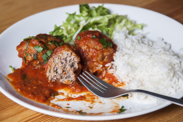 Eating meat balls with tomato sauce and white rice
