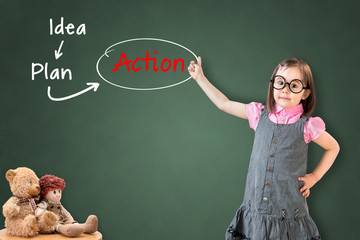 Cute little girl wearing business dress and showing business concept on green chalk board.