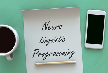 Neuro Linguistic Programming, message on paper, smart phone and coffee on table