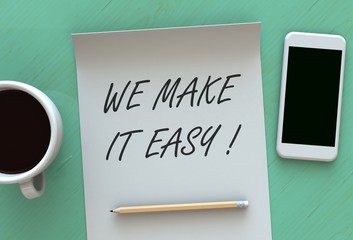 WE MAKE IT EASY, message on paper, smart phone and coffee on table
