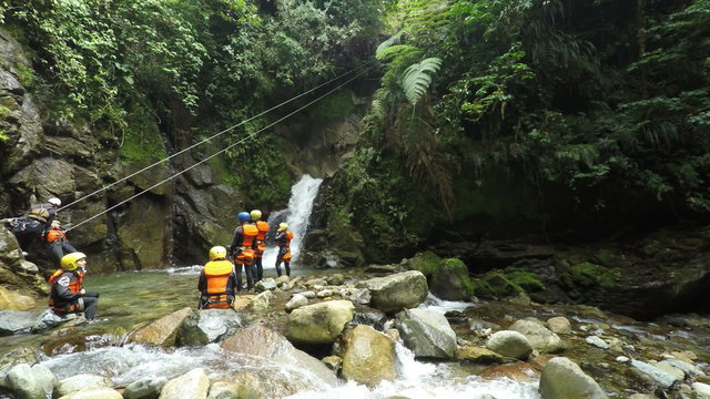 Experience the thrill of canyoning and ziplining in the Ecuadorian rainforest as a group of tourists descend over a stunning waterfall.