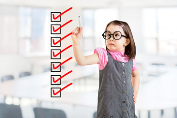 Cute little girl wearing business dress and checking on checklist boxes. Office background.