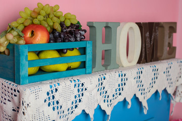 interior. Blue commode against the background of a pink wall. On the dresser letters forming the word "home"