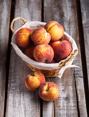 Peaches in knitted basket on old white wooden table in studio