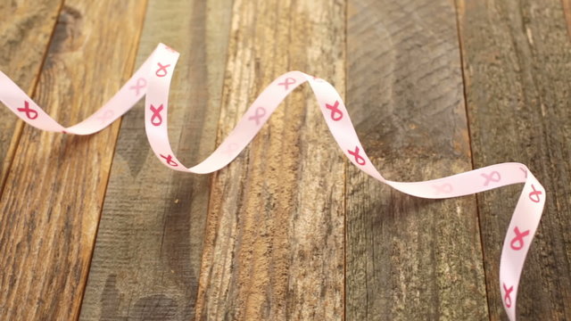 Womens health symbol in pink ribbon on wooden board