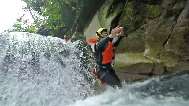Experience the thrill of canyoning in the Ecuadorian rainforest as a young adult female jumps into a mountain river waterfall in stunning slow motion 120fps.