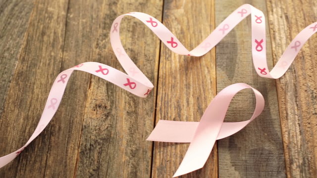 Womens health symbol in pink ribbon on wooden board
