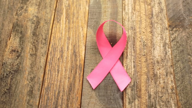 Womens health symbol in pink ribbon on wooden board
