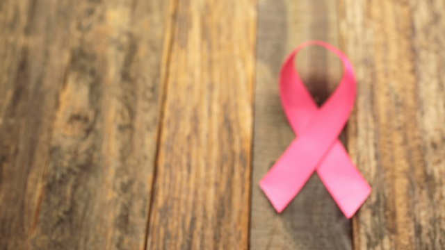 Womens health symbol in pink ribbon on wooden board
