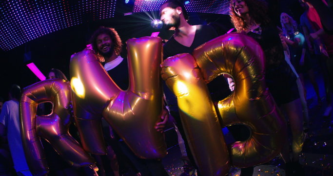 Party group of friends holding balloons saying RnB in club