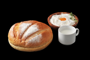 Round loaf of bread, milk in a Cup and the flour