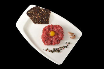 minced beef with raw egg on a white Board tray on black backgrou