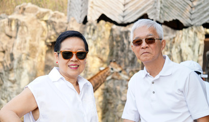 Obraz premium Asian senior couple have fun at zoo. looking at african animal