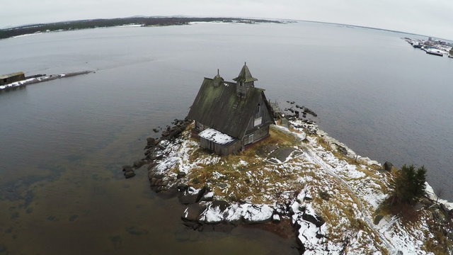Aerial winter shot of solitary house on the waterside with following view to the sea and coastal town Rabocheostrovsk, located near Solovetsky Islands