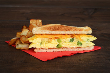 omelette sandwich with fries on red napkin