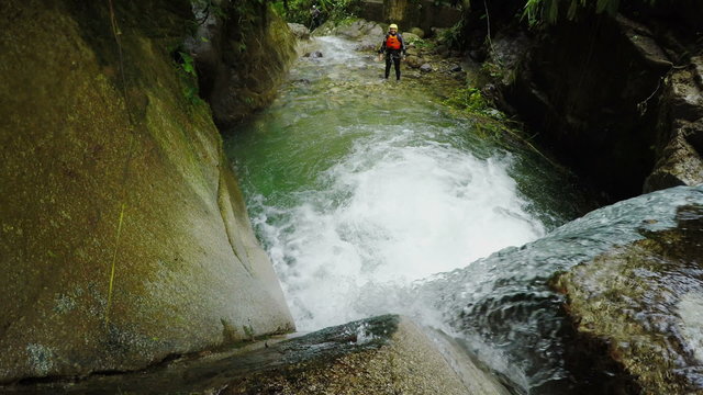Experience the thrill of canyoning in the Ecuadorian rainforest as an adventurous woman fearlessly jumps into a breathtaking waterfall,captured by a static camera with immersive sound.