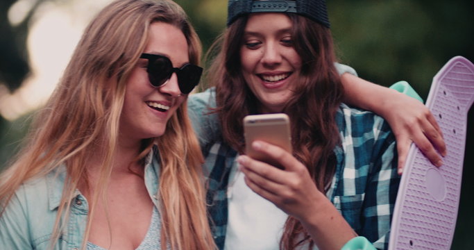 Teen hipster girls laughing at something on mobile phone