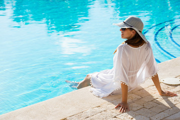 Fashion beautiful woman on summer vacation relaxing at luxury resort spa poolside. Young ...