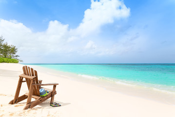 Wooden beach chair with hat and slippers at tropical beach, summer holiday concept