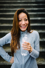 Fitness female athlete spontaneous portrait. Relaxed sporty mixed race latin woman taking a workout rest for drinking water.