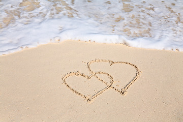 Fototapeta na wymiar Two hearts drawn on the beach sand